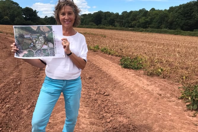 Rebecca Pow pictured on the site of the new station holding a copy of the masterplan