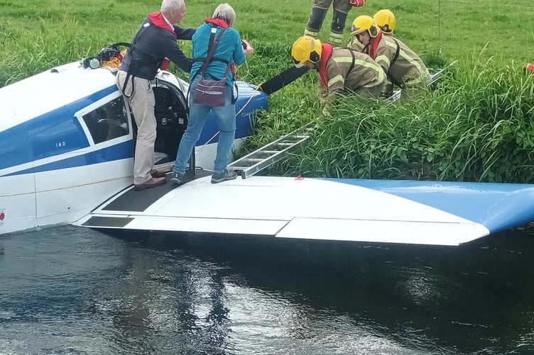 Firefighters help the crashed pilot and passenger from a wing of the aircraft Dunkeswell River Axe