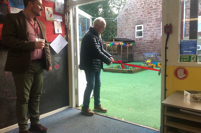 Parish council chairman Cllr Derek Snowden cuts a ribbon to open an early years outdoor area at Langford Budville School, watched by headteacherJonathan Moise-Souch.
