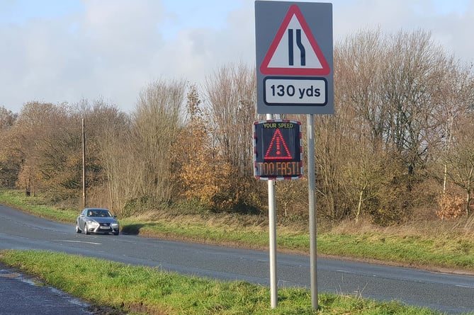 A speed indicator device on the A38 near Perry Elm warns a car approaching off-camera to slow down.