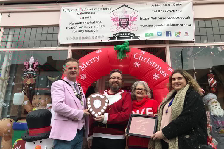 Wellington mayor Cllr Marcus Barr (left) and deputy mayor Cllr Catherine Govier (right) present House of Cake owner Lesley Retallack and front of house Chris Penk with prizes after winning the town's best Christmas shop window competition.
