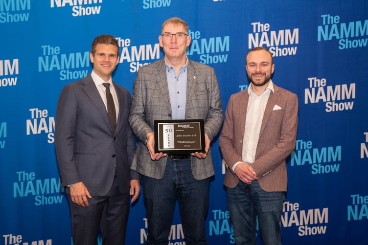 Rob Hanson, centre, and Mark Good, right, of John Packer Musical Instruments, receive the company's NAMM Show Milestone Award, marking 50 years in business, from NAMM CEO, John Mlynczak.