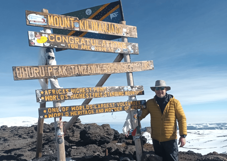 Tim Sandy standing by the mount kilimanjaro sign