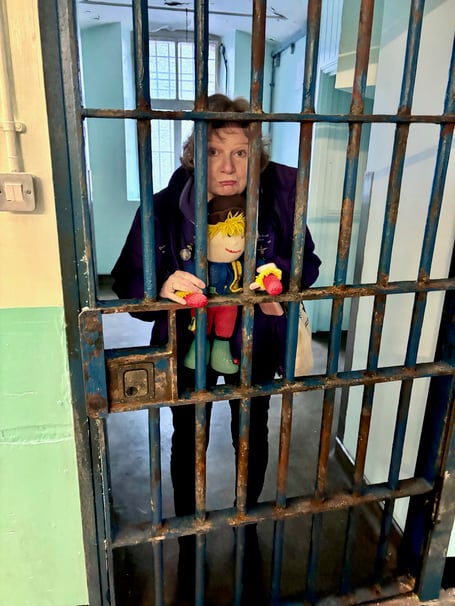 Reminiscence Learning CEO Fiona Mahoney, trying out a Shepton Mallet prison cell with the charity’s mascot Archie.