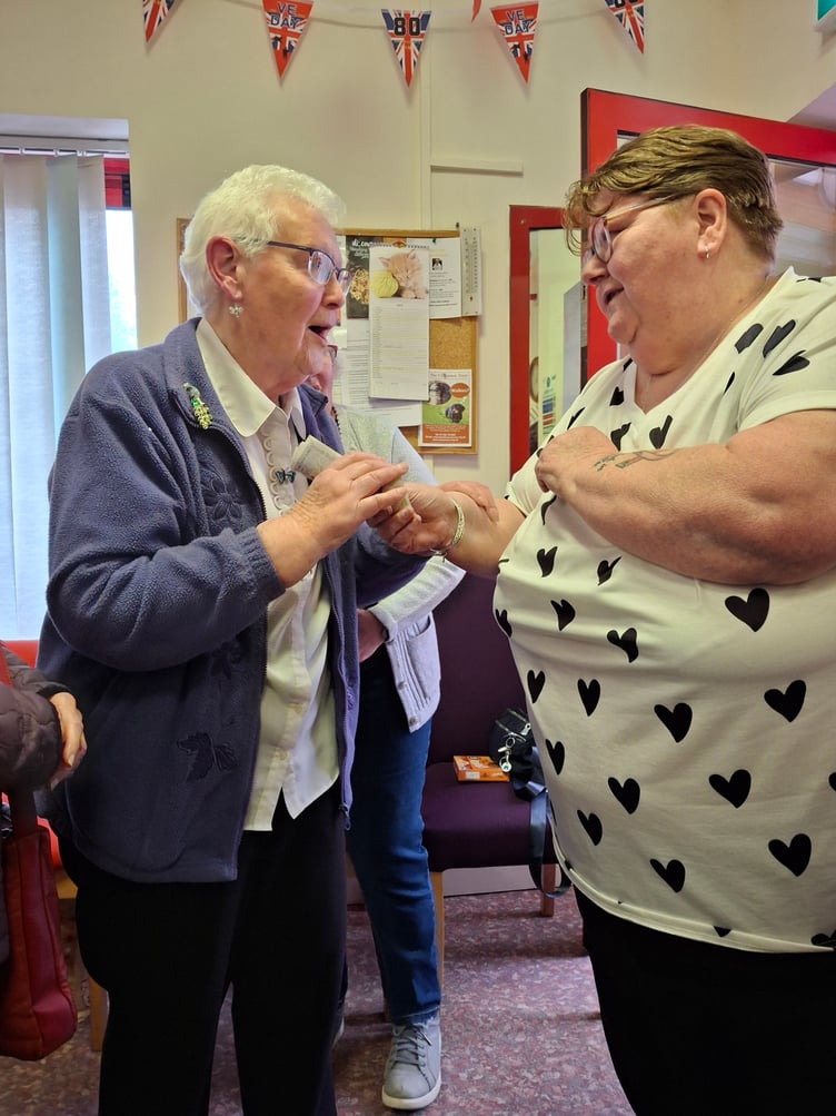 Beryl from Bulford community center recieving £200 from Mary.