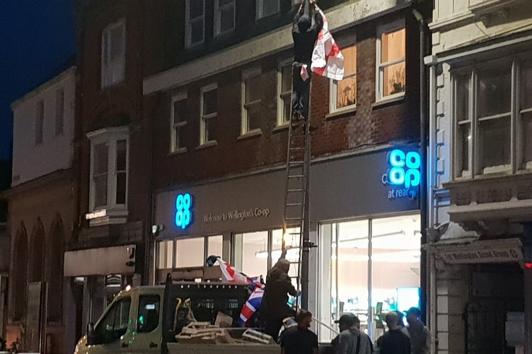 A St George Cross flag being replaced on a lamppost outside Wellington's Co-op supermarket.
