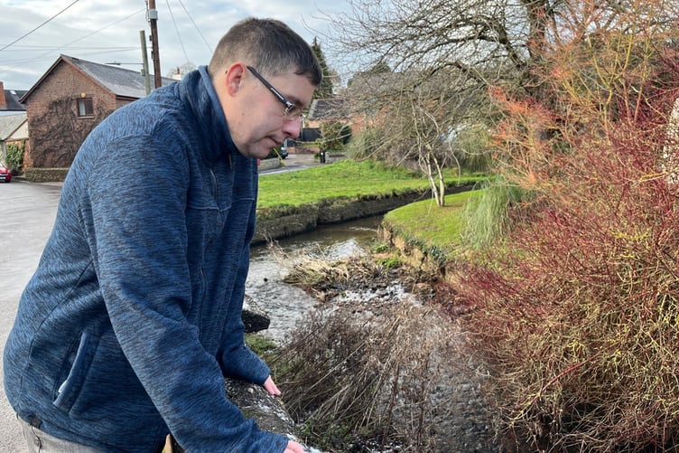 Rockwell Green community advocate Andy Denison inspects the Westford Stream where residents are concerned about flooding risks.