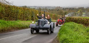 Vintage tractors parade through scenic countryside
