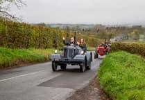 Vintage tractors parade through scenic countryside