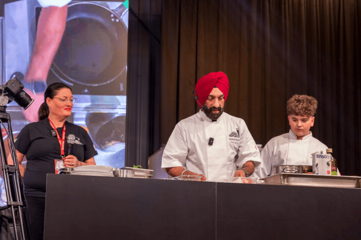 Court Fields School pupil Riel Farinha on stage with celebrity chef Surjan Singh for an extraordinary work experience placement in Lithuania.