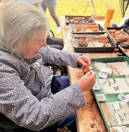 Oaktree Court resident Beryl examining artefacts on her visit to the Halberton excavation. 