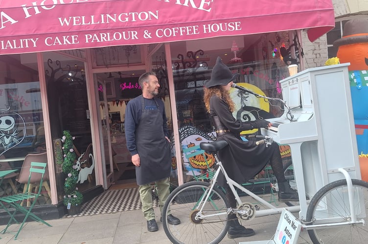 House of Cake's Chris Penk watches piano bike girl Chloe Marie Aston perform outside his Wellington shop on Sunday.